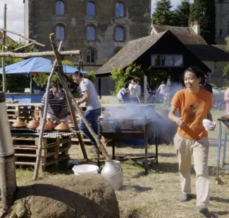 une femme avec un teeshirt orange dans un jardin pres d'un barbecue